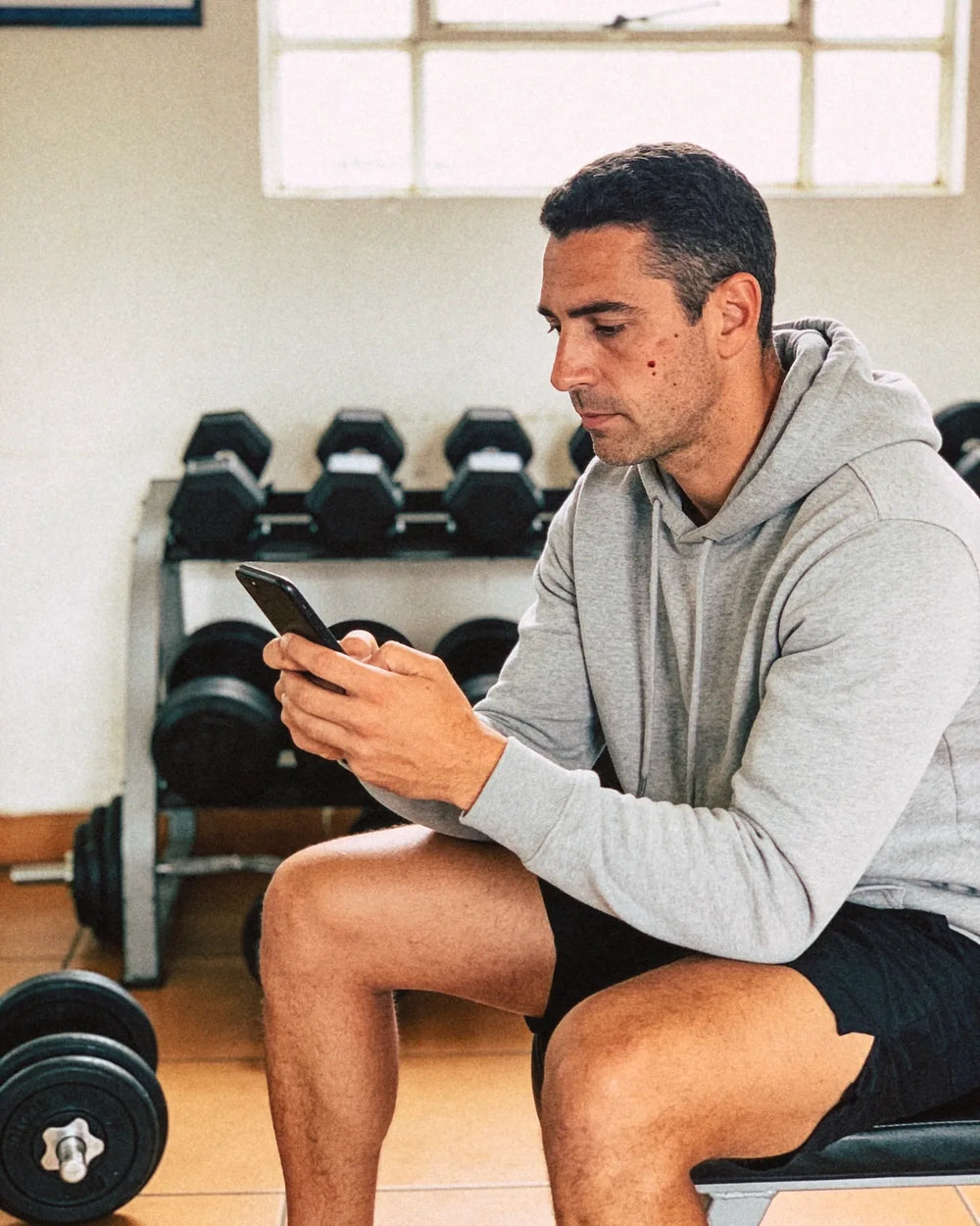 Entrenador personal con el celular en un gimnasio