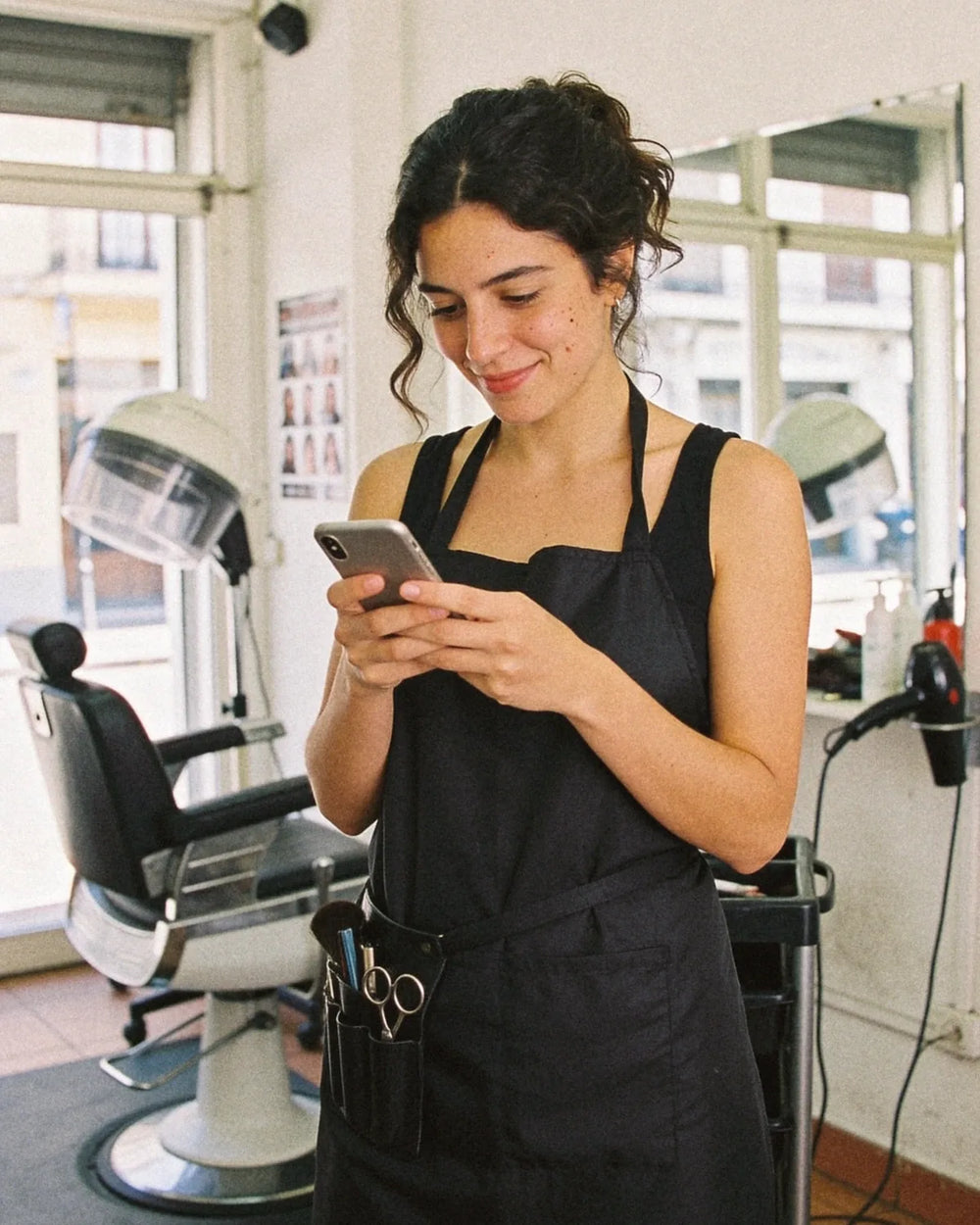 Peluquera mirando el celular en su peluquería